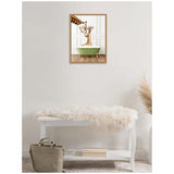 Framed canvas of a mother giraffe kissing her baby in a pale green clawfoot bathtub, hung above a white bench with a fluffy cushion and beige bag below