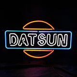 Neon sign with white "DATSUN" text inside a blue rectangular outline, overlaid on an orange semicircle top and bottom against a black background.
