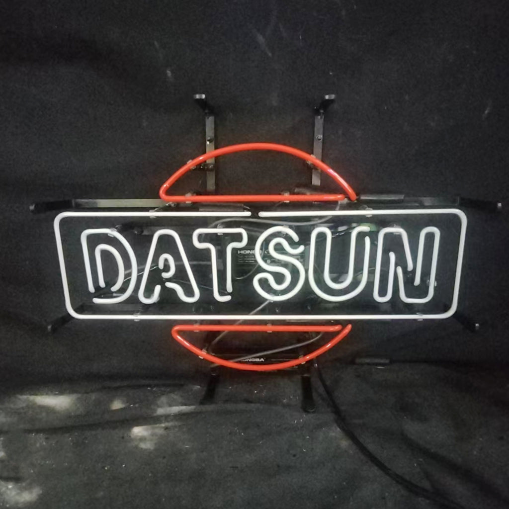 Neon sign displaying the word 'DATSUN' in white letters framed by a rectangular outline with a stylized red circle partially intersecting it against a dark background.