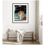 Framed photograph of a tiger walking across an urban street crosswalk at night, with street signs and building lights in the background, hung above a wooden bench with a folded cloth.