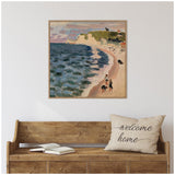 Framed canvas print of an impressionist coastal scene with a deep blue sea meeting a sandy beach, green cliffs in the background, hanging above a rustic wooden bench with a 'welcome home' pillow and open book.