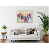 Abstract horizontal canvas with colorful vertical brushstrokes in pink, blue, orange, and white, framed in light wood, hanging above white sofa with patterned pillows