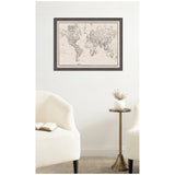Vintage-style black and white world map with detailed country borders on a fabric pinboard framed in dark wood, hanging above a brass side table and cream armchairs.