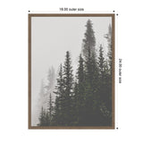Sylvie framed canvas depicting tall, dark green pine trees fading into a misty gray background, framed in simple brown wood measuring 18x24 inches.