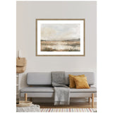 Framed abstract landscape in neutral tones above gray sofa with gray blanket and mustard pillow, featuring soft earth and sky hues in muted brushstrokes.