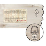 Back view of a pale wooden wall art with a certificate label and a close-up of a D-ring metal hanger attached by a screw.