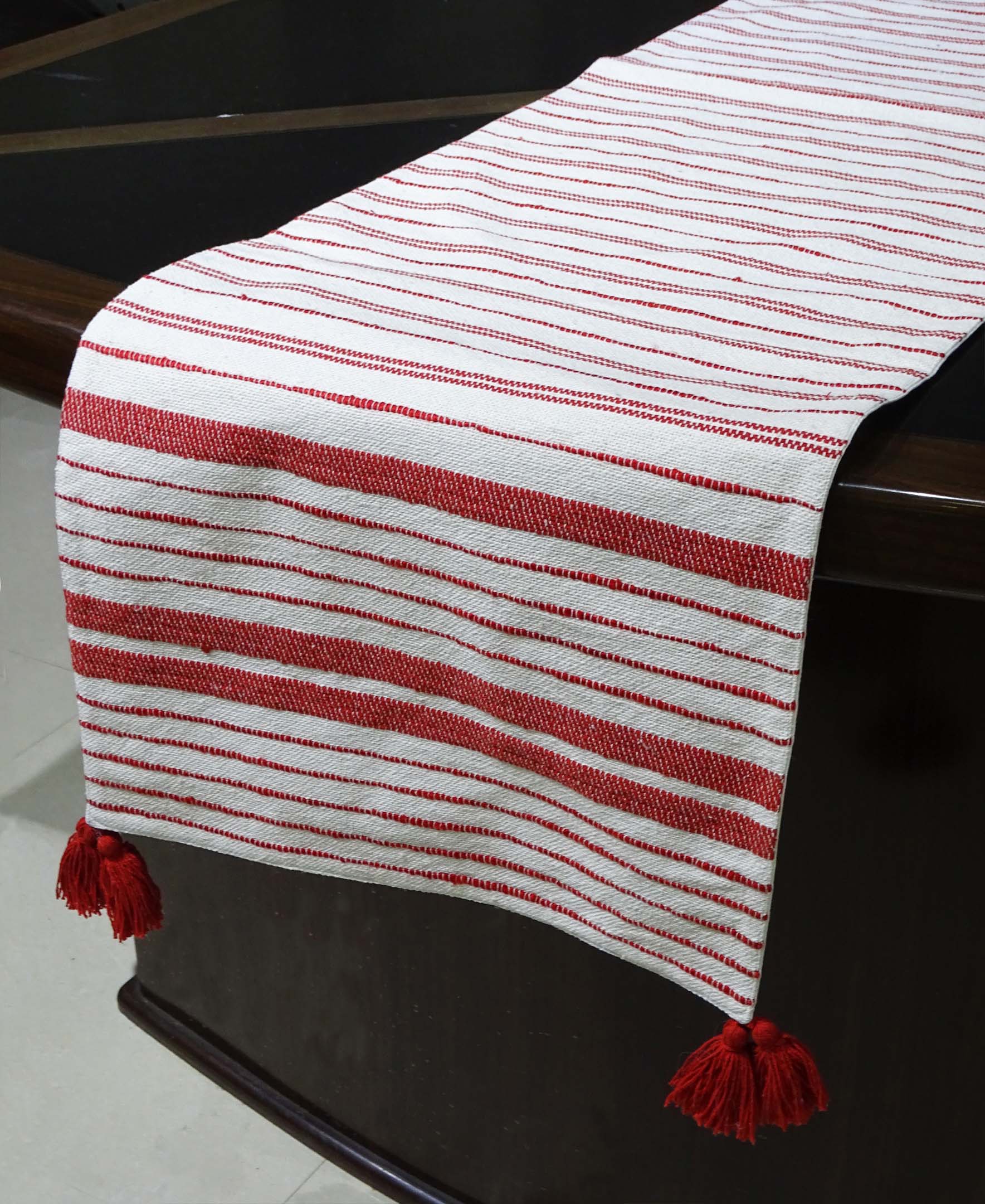 Woven cotton table runner in off white and red laid on a dining table
