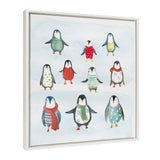Framed canvas with watercolor-style penguins wearing colorful patterned sweaters and scarves on a blue snowy background.
