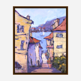 Impressionistic painting of a narrow street lined with beige buildings with red roofs leading to a blue lake with distant sailboats and hazy purple hills under a light sky.