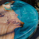 Close-up of a round tabletop featuring light wood grain with natural knots beside glossy, swirling translucent blue epoxy resin that mimics water.
