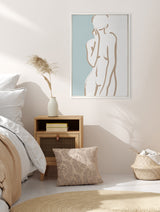 Minimalist bedroom corner with beige and white bedding, wooden nightstand holding a vase with pampas grass, and wall art featuring abstract tan line figure on teal background.