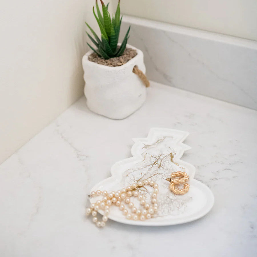 Resin Ceramic Snowman Tray in a pot on a marble surface with jewelry and a mirror in the background.