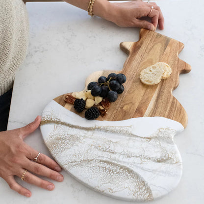 Person arranging food on a Snowman Acacia Resin Board with marble base and wooden top.
