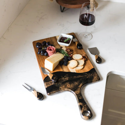 Wooden resin charcuterie board with cheese, grapes, and a glass of red wine on a white surface.