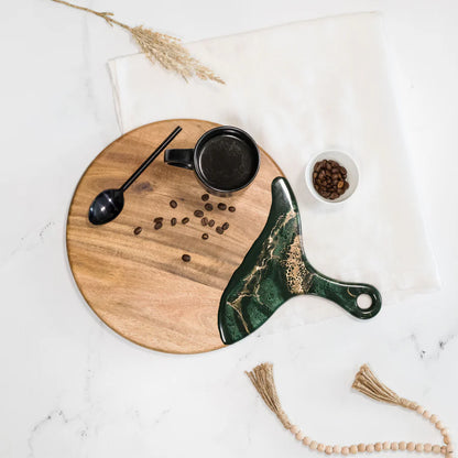 Wooden Cheese Paddle Acacia Serving Charcuterie Board with a marble handle knife, black mug, and coffee beans on a white surface.