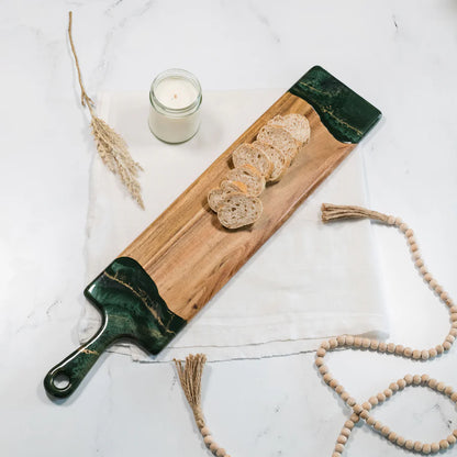 Wooden baguette resin serving tray with green edges, bread slices, and a candle on a light background