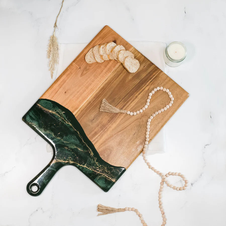 Wooden charcuterie serving tray with a green marble-patterned knife on a white surface.