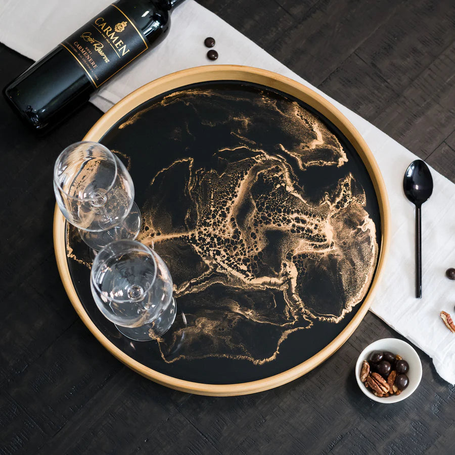 Decorative serving tray with a map design on a table with wine bottle, glasses, and bowl.