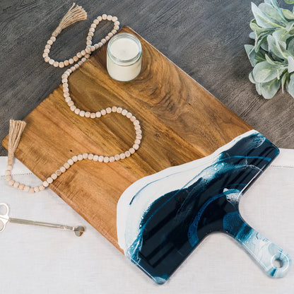 Wooden charcuterie serving tray with a blue and white decorative item on a wooden surface.