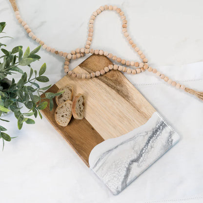 Wooden resin charcuterie board with marble accents and bread slices on a white surface with a plant.