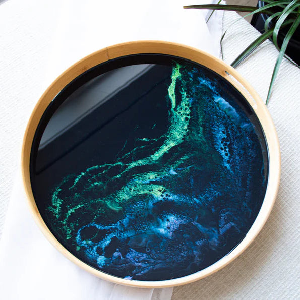 Round serving tray with a green and blue abstract design on a white surface