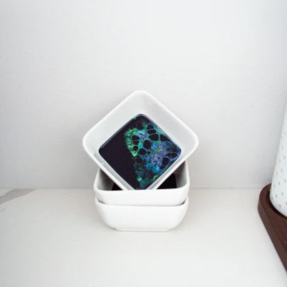 Stack of white ceramic resin bowls with a colorful pattern on a white surface