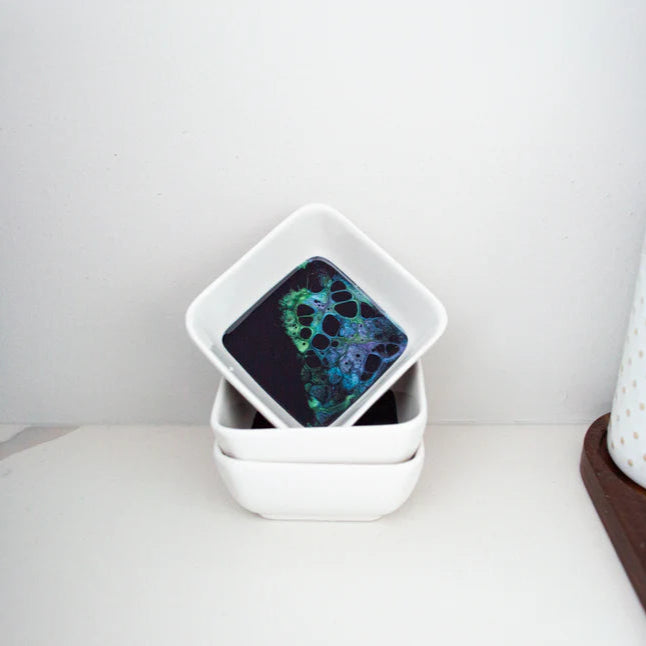 Stack of white ceramic resin bowls with a colorful pattern on a white surface