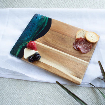 Wooden resin charcuterie board with fruits, cheese, and meats on a white surface