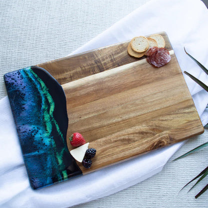 Wooden acacia resin serving bread board with a knife and fruits on a white surface