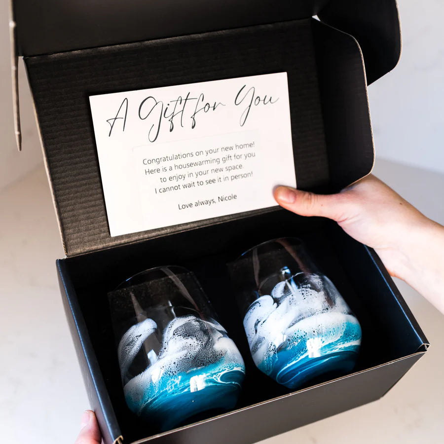 Two blue and white resin wine glasses in a black box with a card inside.