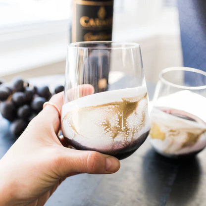 Person holding a resin wine glass with a bottle of Calvados in the background
