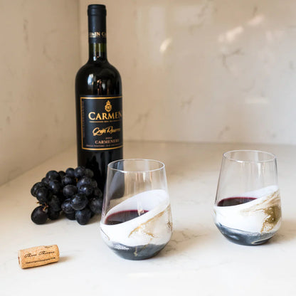 Bottle of Carmel wine with two resin wine glasses and grapes on a marble surface