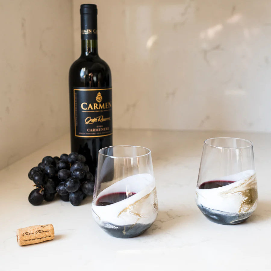 Bottle of Carmel wine with two resin wine glasses and grapes on a marble surface