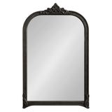 Arched wall mirror with dark ornate frame featuring decorative elements at the top center and curved corners, reflecting a plain light background.
