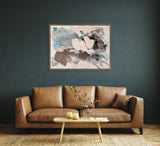 Abstract painting with gray, white, blue, and brown washes in a wooden frame, hanging on a dark teal wall above a tan leather sofa with a wooden coffee table in front.