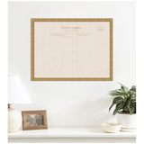 Large framed linen pinboard designed to resemble a vintage postcard with beige fabric and muted brown text, hung on a white wall above a white shelf with decor.