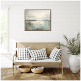 Framed abstract gray and green horizon painting hangs above a light wood bench with three black-and-white checkered pillows, beside a large white vase with green foliage.