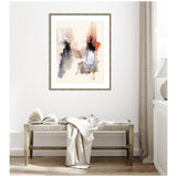 Abstract watercolor wall art with muted browns, black, and rust hues framed in weathered wood, displayed above a rustic wooden bench with a draped light cloth and open book.