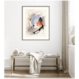 Abstract watercolor painting with soft blue, orange, and black brushstrokes framed and hung above a wooden bench with a draped white cloth and an open book.