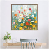 Colorful wildflower garden painting with red, orange, pink, yellow, and white flowers against a soft blue-green background in a decorative frame above a desk and chair.