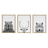 Three framed black and white canvases showing close-up portraits of a bear, a deer with prominent antlers, and a wolf against plain white backgrounds.