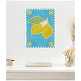 Framed canvas artwork of two yellow lemons with a green leaf on a bright blue background, bordered by a checkerboard and sun motifs in each corner.