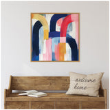 Square abstract painting with bold curved brushstrokes in navy, red, yellow, pink, and white in a thin wooden frame above a rustic wooden bench with an open book and 'welcome home' pillow.