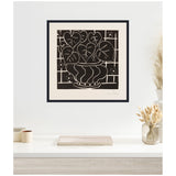 Black and white framed art print of stylized begonia leaves and flowers in a wavy-lined vase against a geometric grid background, hanging above a minimalist desk with dried plants.