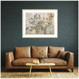 Framed abstract olive tree wall art with muted beige and green tones above a brown leather sofa against a dark green wall, next to a wooden coffee table with glass vase.