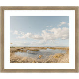 Framed art print titled Marshland by Crystal Lynn Collins showing a marsh landscape with waterway and golden reeds under a vast sky with scattered clouds