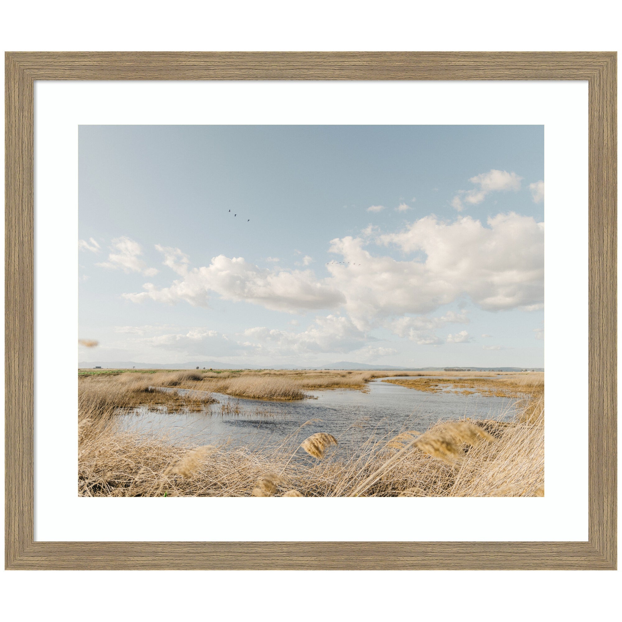 Framed art print titled Marshland by Crystal Lynn Collins showing a marsh landscape with waterway and golden reeds under a vast sky with scattered clouds