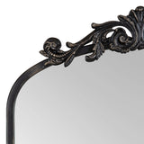 Upper section of an arched mirror with ornate black carved frame featuring scroll and leaf motifs, showcasing a traditional decorative style.