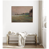 Framed canvas of a misty twilight landscape with a glowing moon, dark trees on right, soft green and brown tones, hung above wooden bench with open book and draped cloth.