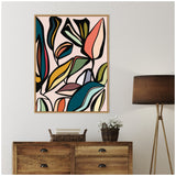 Abstract botanical wall art with bold, colorful leaves outlined in black on a light pink background above a wooden dresser and a tall lamp with a dark brown shade.